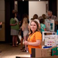 student ready for visitors at her table during student project showcase